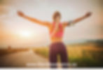 A runner with outwardly stretched arms, feelilng refreshed after a jog on a country road.