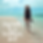 a picture of a woman walking alone on  the beach on a sunny clear day.